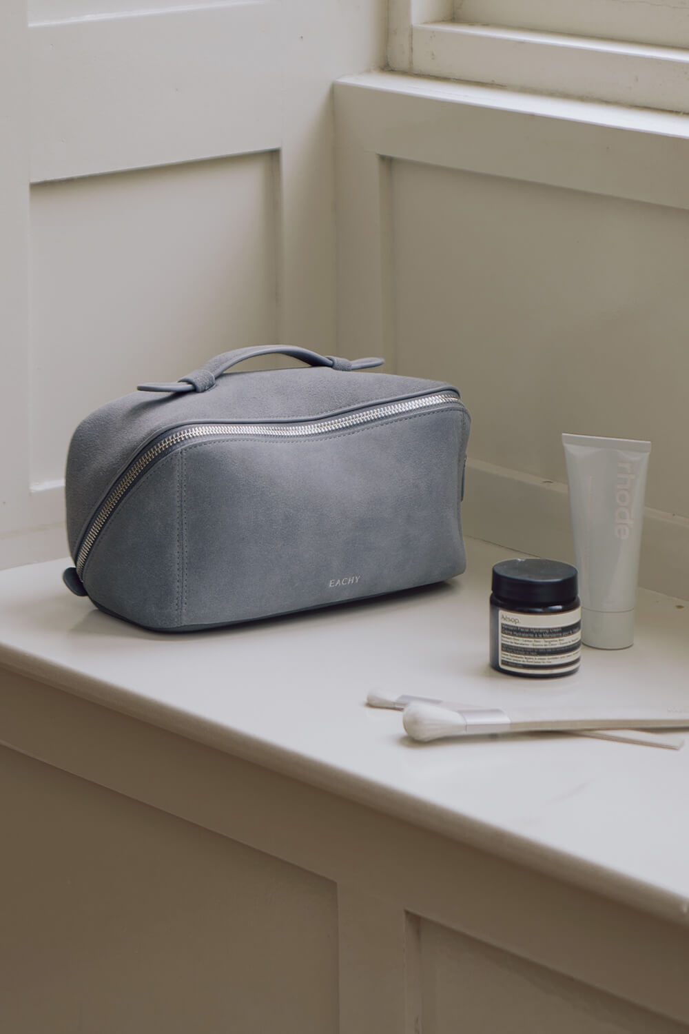 Lifestyle shot of blue handheld cosmetic bag on window sill, essential travel organizer case
