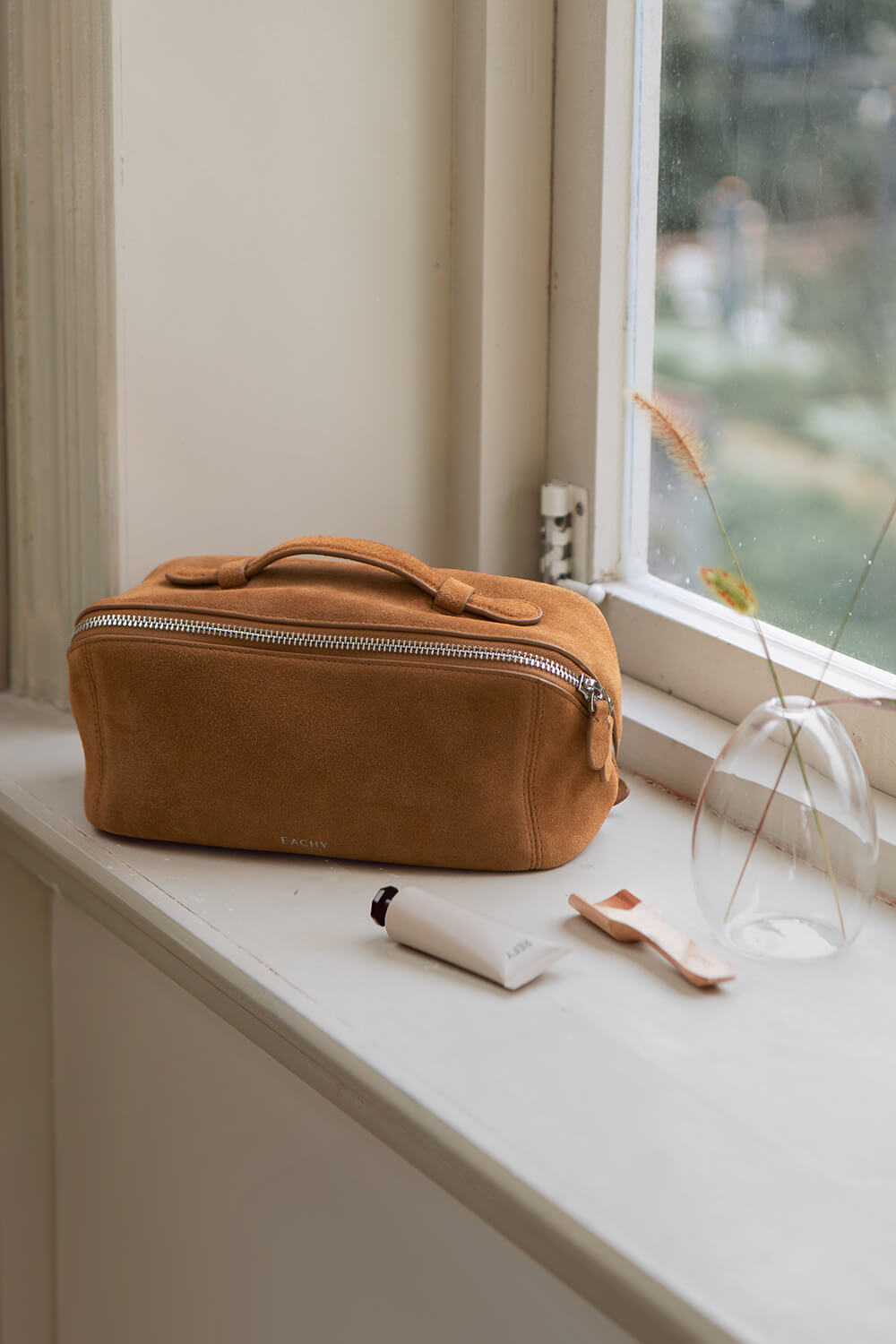 Large capacity caramel brown makeup bag open on bed, showing spacious interior for travel essentials