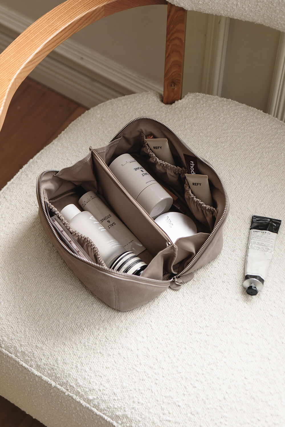 Open travel toiletry organizer for skincare storage displayed on chair