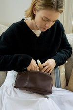 Model accessing black makeup bag contents, large capacity travel cosmetic bag for women.