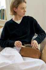 Woman holding camel brown makeup bag, classic leather travel cosmetic bag.