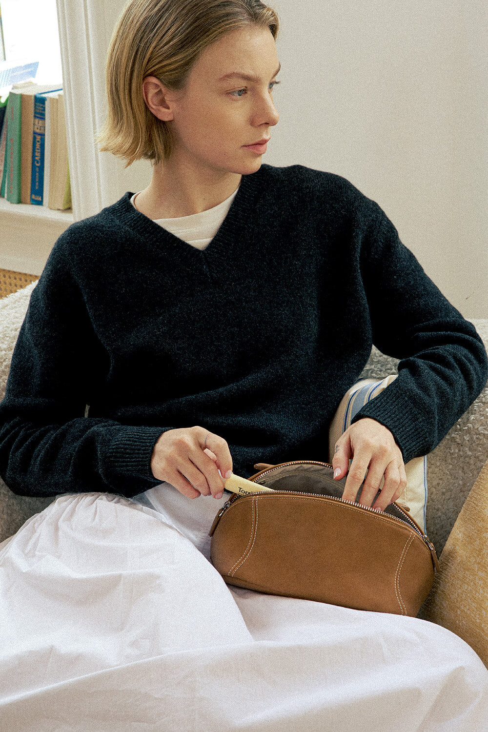 Woman holding camel brown makeup bag, classic leather travel cosmetic bag.