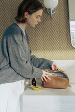 Lifestyle shot of brown makeup bag in bathroom, essential travel toiletry bag.