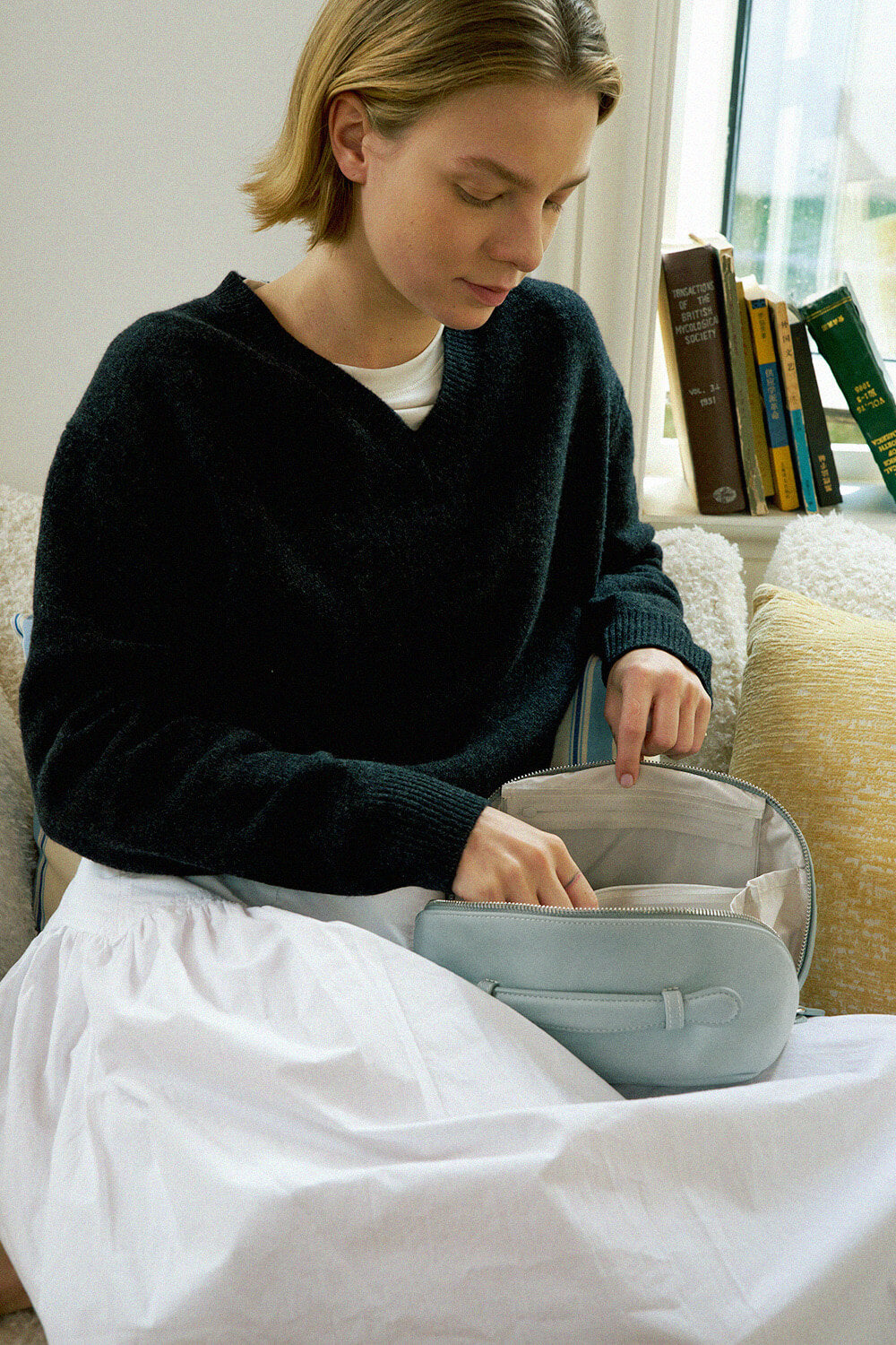 Model holding light blue makeup bag, aesthetic travel cosmetic bag for women.