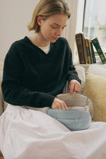 Model holding light blue makeup bag, aesthetic travel cosmetic bag for women.