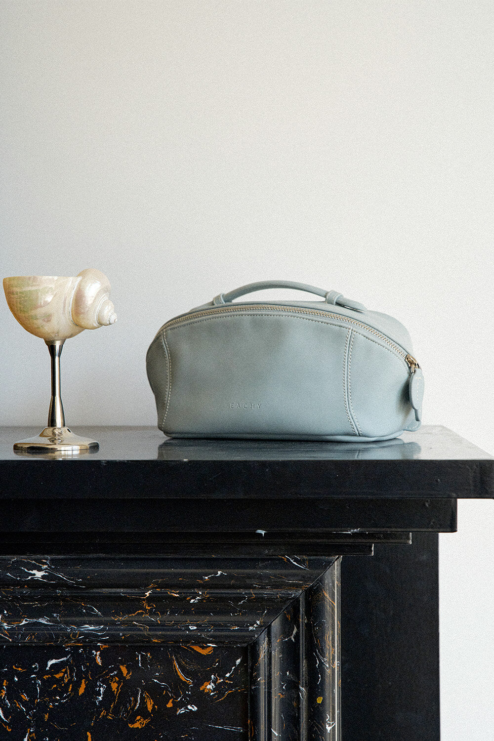 Blue leather makeup bag on dark table, elegant travel toiletry bag organizer.