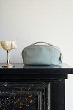 Blue leather makeup bag on dark table, elegant travel toiletry bag organizer.