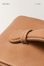 Close-up of brown makeup bag stitching detail, premium travel cosmetic bag material.