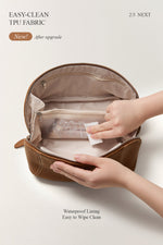 Hands showing easy-to-clean lining of brown makeup bag, travel toiletry bag feature.