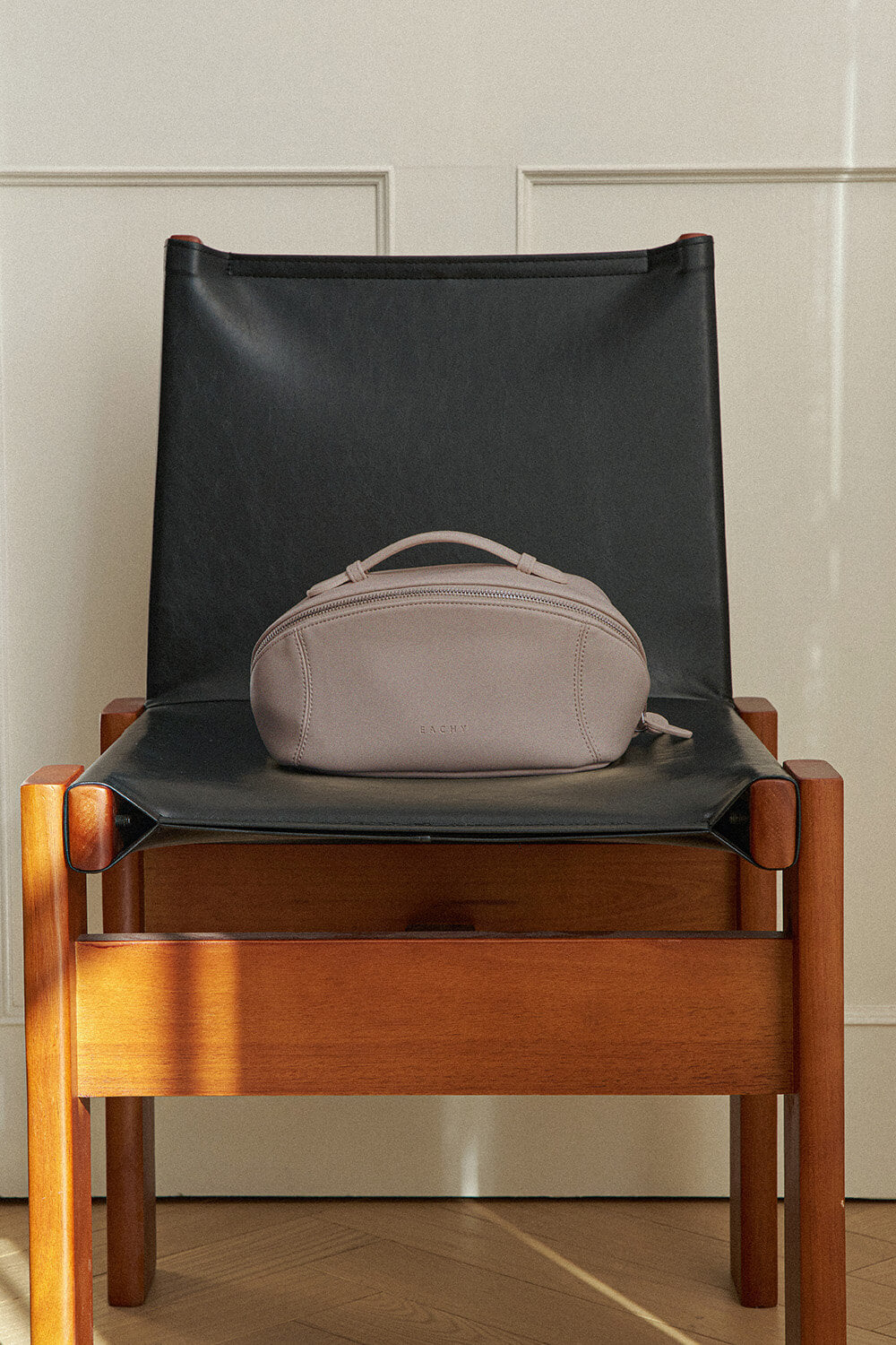 Mauve purple makeup bag on chair, modern aesthetic travel cosmetic bag.