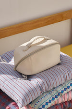 Minimalist white cosmetic bag displayed on dark vanity shelf